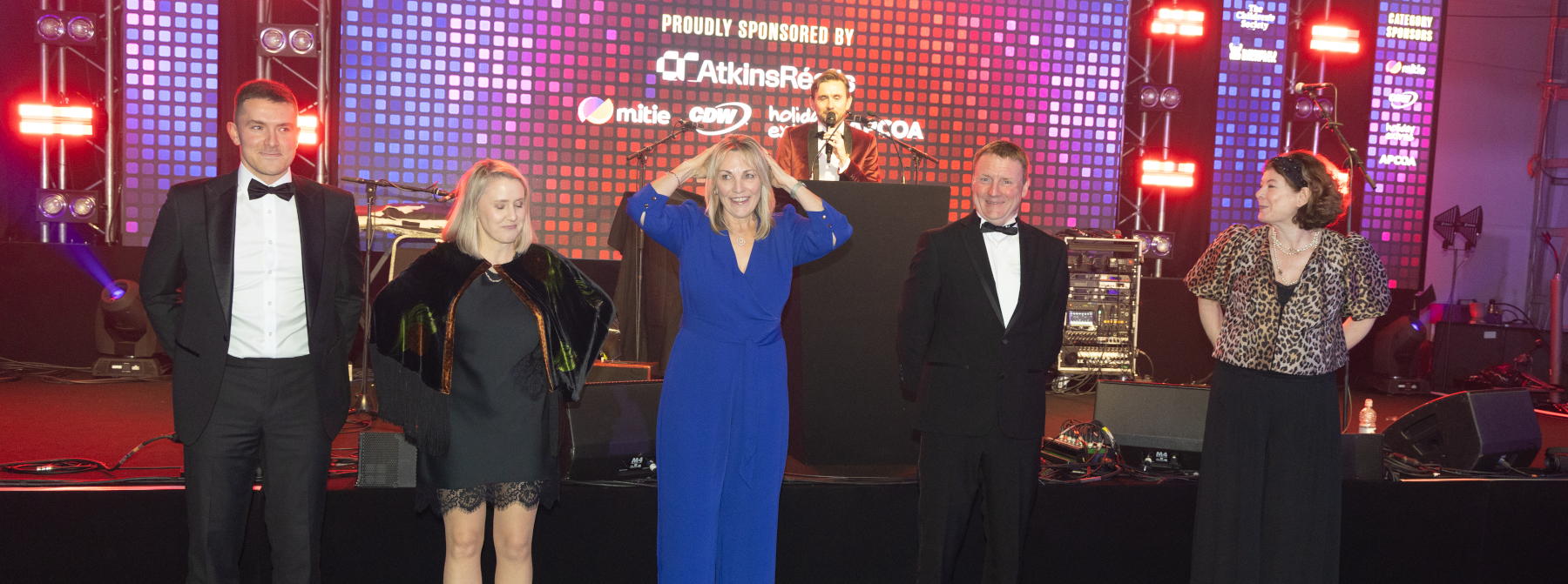 Kevin Durham hosting a game show round with guests lined up on stage at the MAG-FEST gala
