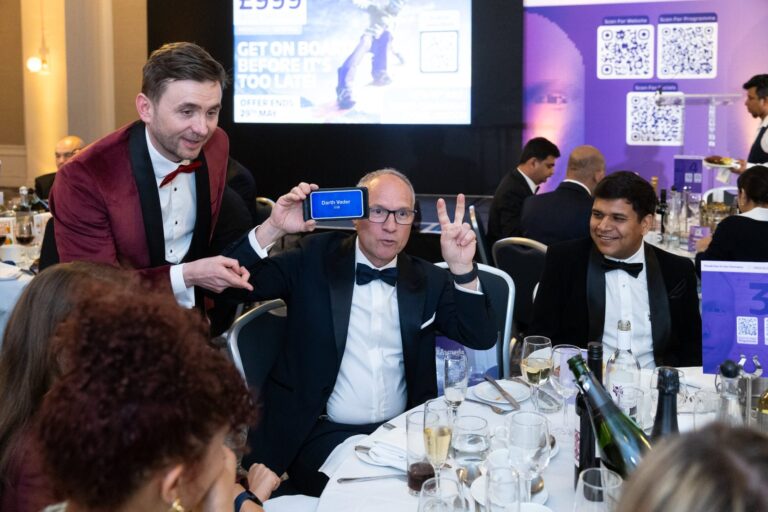 Kevin Durham holding a phone to a guest&rsquo;s forehead during Heads Up at a black-tie dinner
