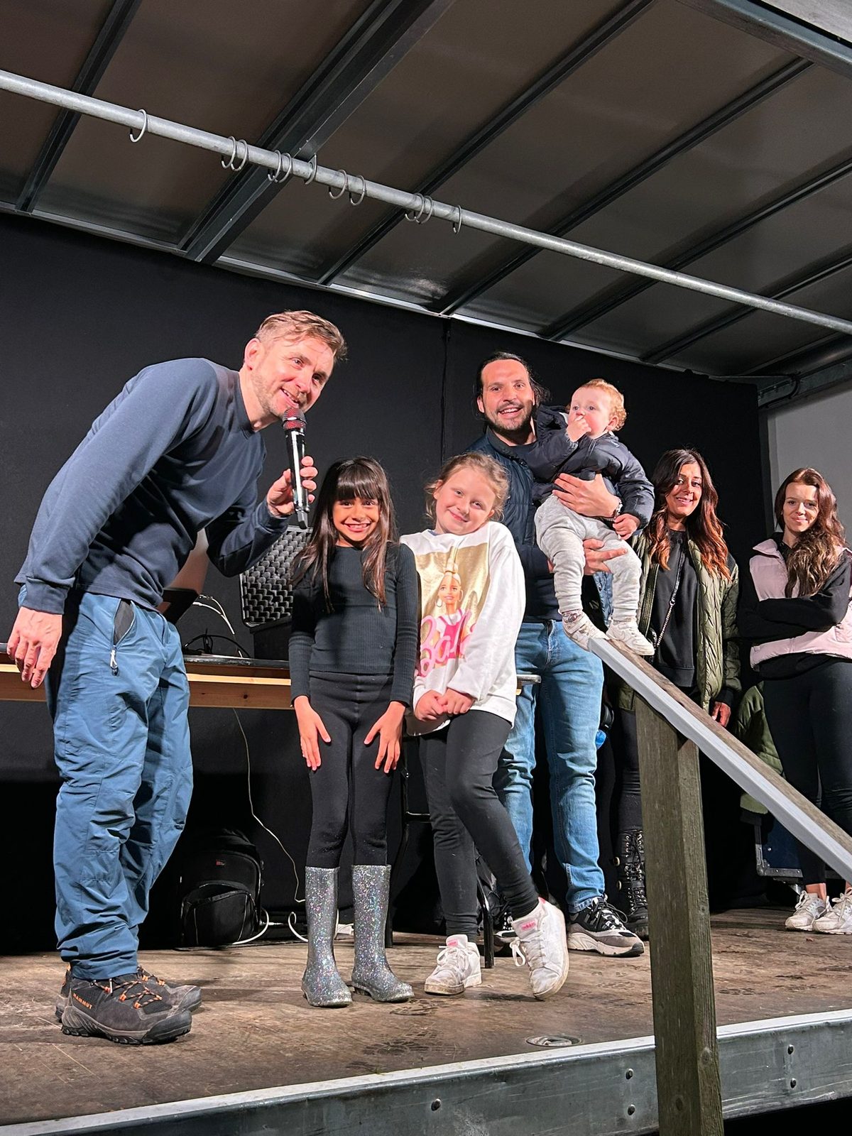 Kevin Durham on stage with a microphone, hosting children and their families at a family festival