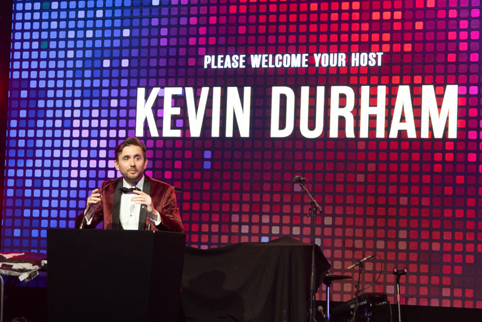 Kevin Durham introduced as host with his name in lights on stage